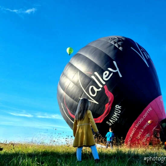 Une enfant devant une montgolfière qui se gonfle