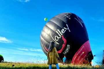 Une enfant devant une montgolfière qui se gonfle