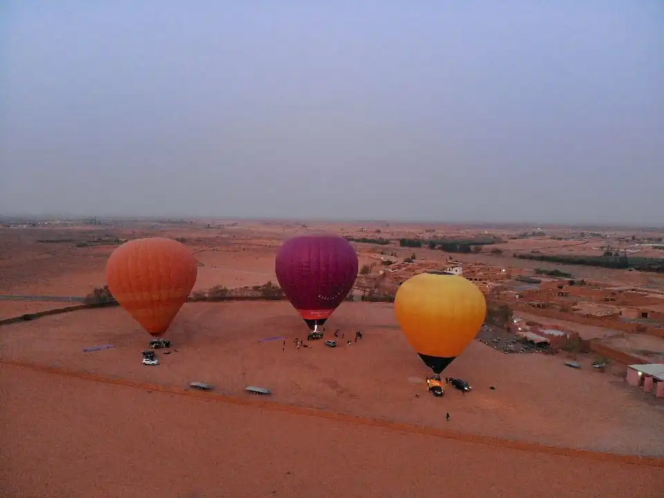 Trois montgolfières au décollage près de la palmeraie de Marrakech.