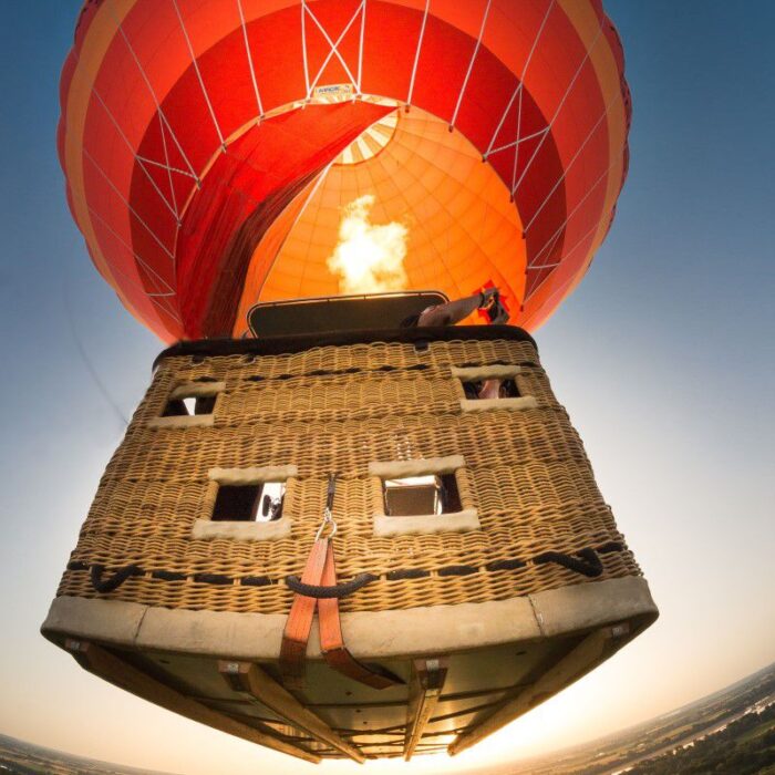 Montgolfière orange et rouge au décollage.