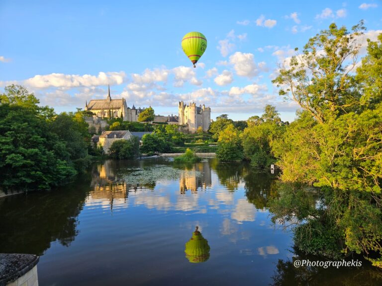 Montgolfière verte en vol proche du château de Montreuil Bellay se reflétant dans la rivière